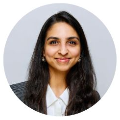 Pankhuri smiles at the camera wearing a white collared shirt and grey blazer.