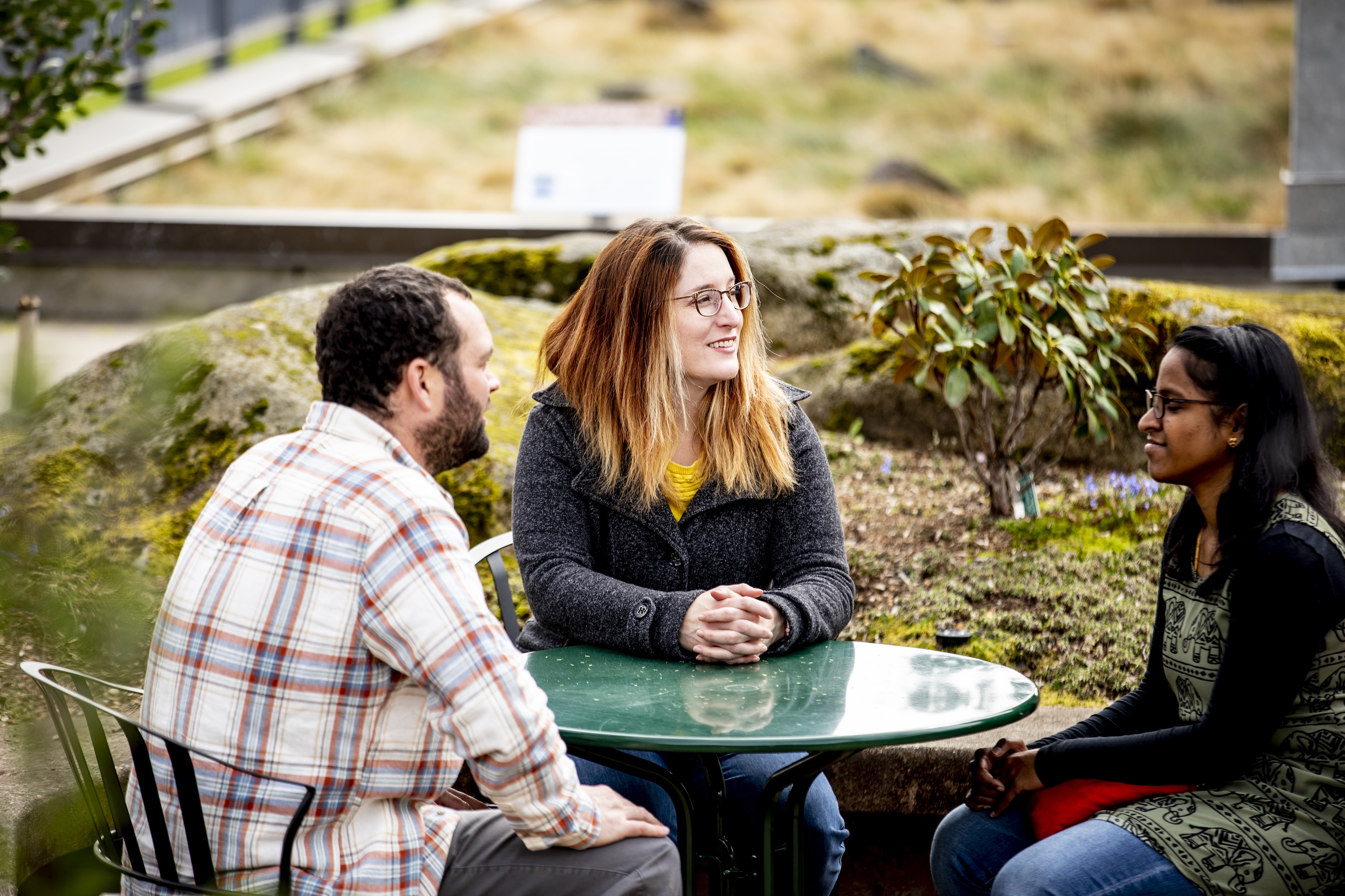 Three people sitting at an outdoor table.