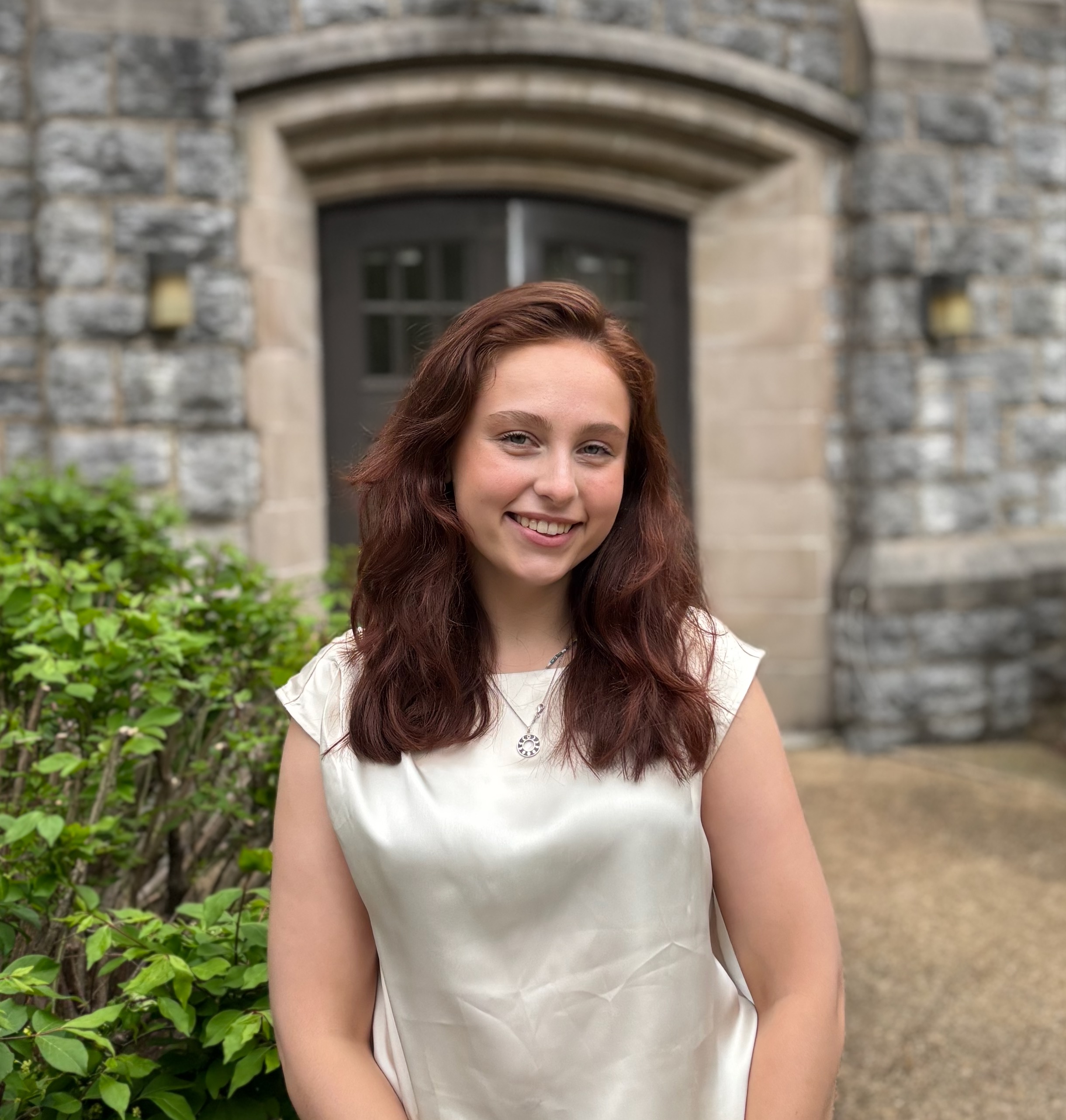 Emma Clevelan looks at the camera standing in front of an exterior doorway.