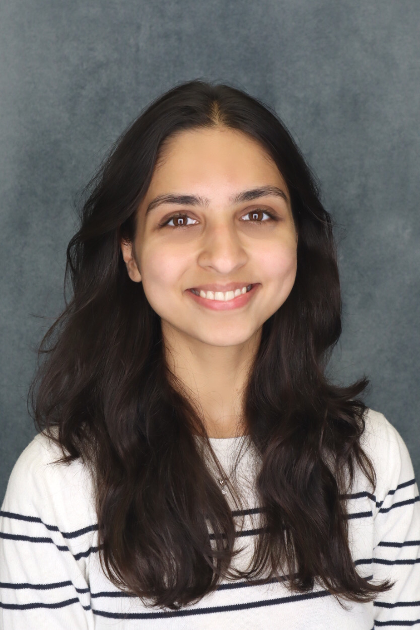 Pankhuri looks at the camera wearing a white sweater with black stripes.
