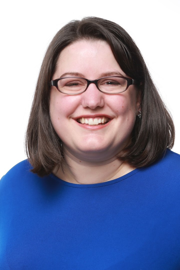 Kathleen smiles at the camera wearing a blue top.