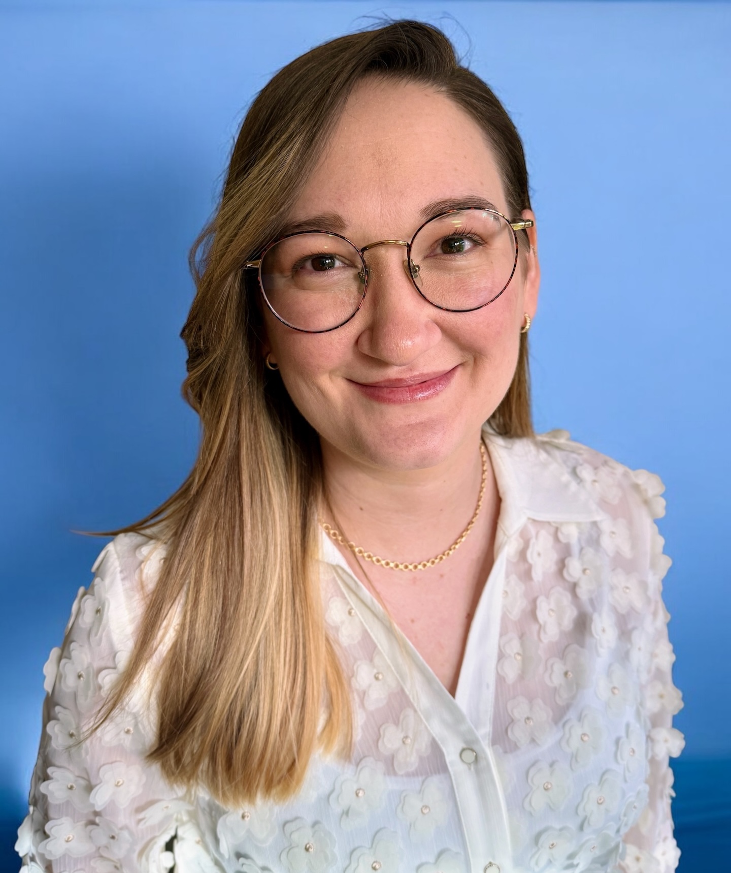Jenny smiles at the camera in front of a blue background.